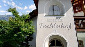 A building with a sign reading 'RESIDENCE Tischlerhof' and a window with a view of mountains. - Holiday Apartment "Tischlerhof - Typ B" with Wi-Fi, Terrace and Mountain View (Dorf Tirol bei Meran)