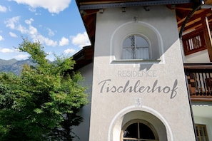A building with a sign reading 'RESIDENCE Tischlerhof' and a window with a view of mountains.