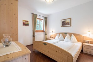 A wooden bed in a room with a window, a bedside table, and a nightstand.