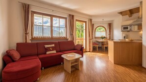Ett kompakt bostadsutrymme med en soffa, ett litet bord, en köksdel med mikrovågsugn och ett matbord.