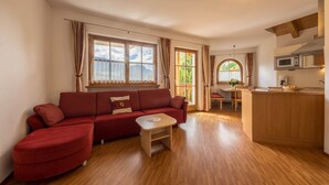 Una sala de estar con un sofá rojo, una mesita de madera y una zona de cocina con microondas.