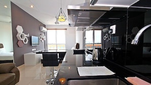 Una cocina moderna con una isla grande, un comedor con barra y un espacio de sala de estar con sofá.