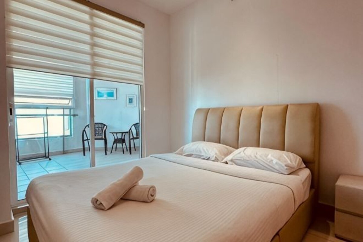Ein Hotelzimmer mit einem Bett, einem kleinen Tisch und einem Stuhl in der Nähe einer Glastür zu einem Außenbereich.