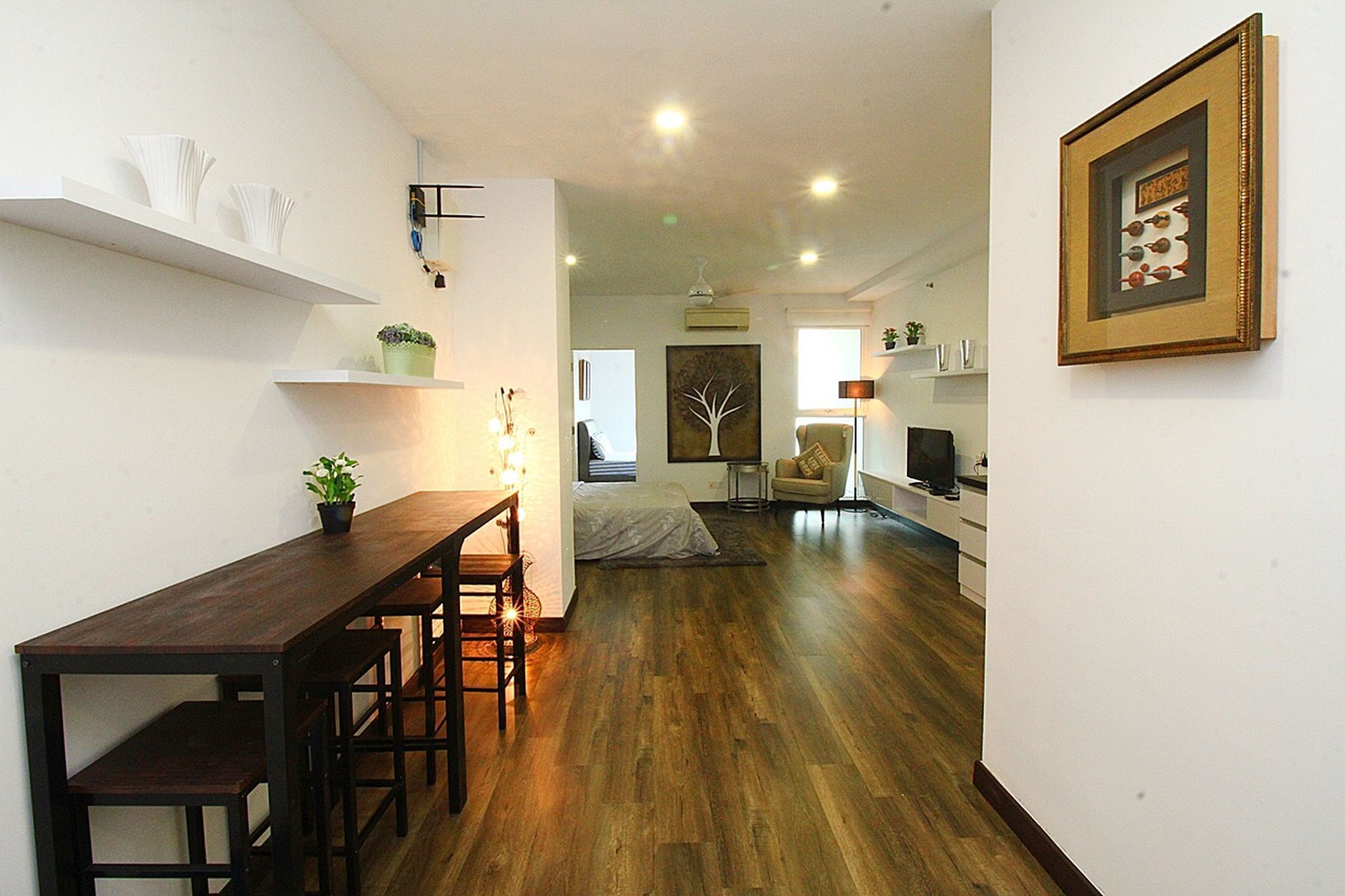 Een moderne woonkamer met een houten vloer, een eettafel met stoelen, een bank en een televisie.
