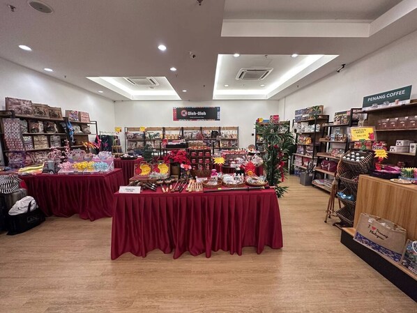 A retail store with multiple tables displaying various products, including toys and crafts, under bright lighting. - Mansion One Suites By Merlene (George Town)