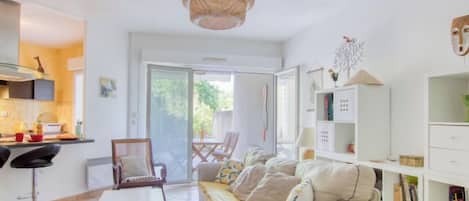 A bright living room with a sofa, a dining table, and a bookshelf.