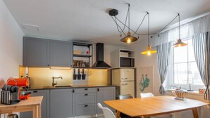 Een moderne keuken met grijze kastjes, een houten eettafel en een koffieapparaat.