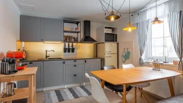 Une cuisine moderne avec des meubles de couleur grise, une table à manger en bois et une machine à café.