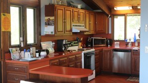 A kitchen with wooden cabinets, a stainless steel dishwasher, a microwave, and a stove. - Spend your vacation at this relaxing waterfront retreat on Green Hill Pond. (South Kingstown)