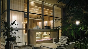 A modern outdoor seating area with metal chairs and a sofa, a large potted plant, and a well-lit interior visible through large windows. - Zentis Osaka (Osaka)