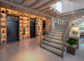 Un intérieur moderne avec un escalier, des étagères et un espace d’ascenseur bien éclairé.