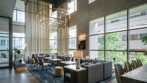 A spacious, modern lounge area with a large seating arrangement, a central chandelier, and large windows offering views of the cityscape. - Zentis Osaka (Osaka)