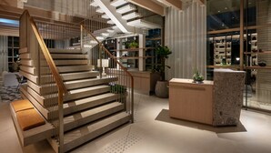 A modern interior with a wooden staircase, a reception desk, and a glass display area. - Zentis Osaka (Osaka)