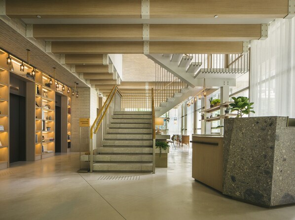 Un vestíbulo amplio con una escalera, estanterías y una zona de recepción.