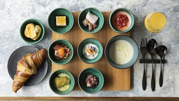 A breakfast spread on a wooden board with various dishes and a croissant.