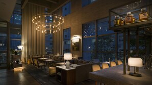 A modern lounge area with a bar, seating, and large windows offering views of the cityscape. - Zentis Osaka (Osaka)