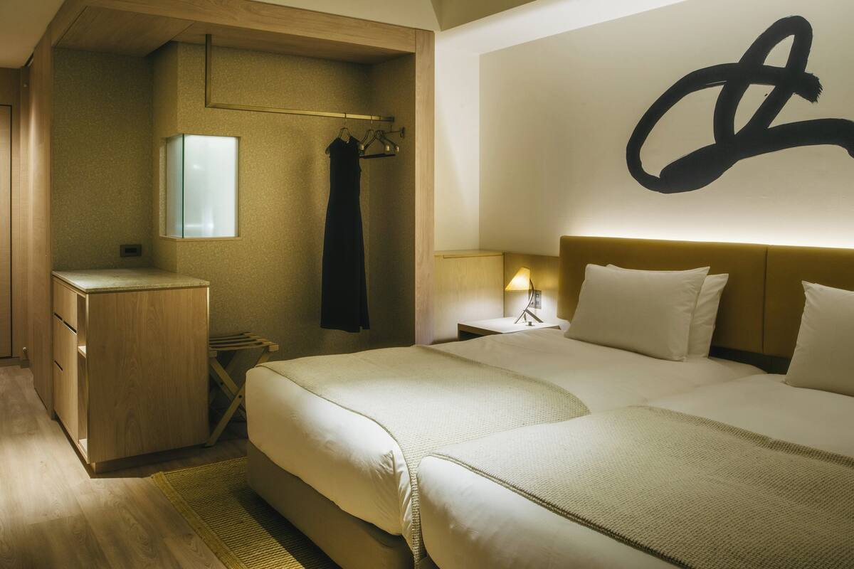 A hotel room with a large bed, a bedside table with a lamp, a wardrobe, and a mirror.