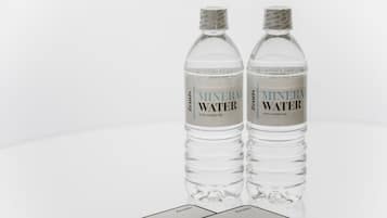 Deux bouteilles d’eau minérale transparentes, avec étiquettes, et une carte posée sur une surface réfléchissante.
