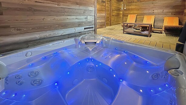 A hot tub with blue LED lights, wooden walls, and two chairs with cushions. - Les Granges de Sarreyer - 10 mns from Verbier - Sw (Sarreyer)