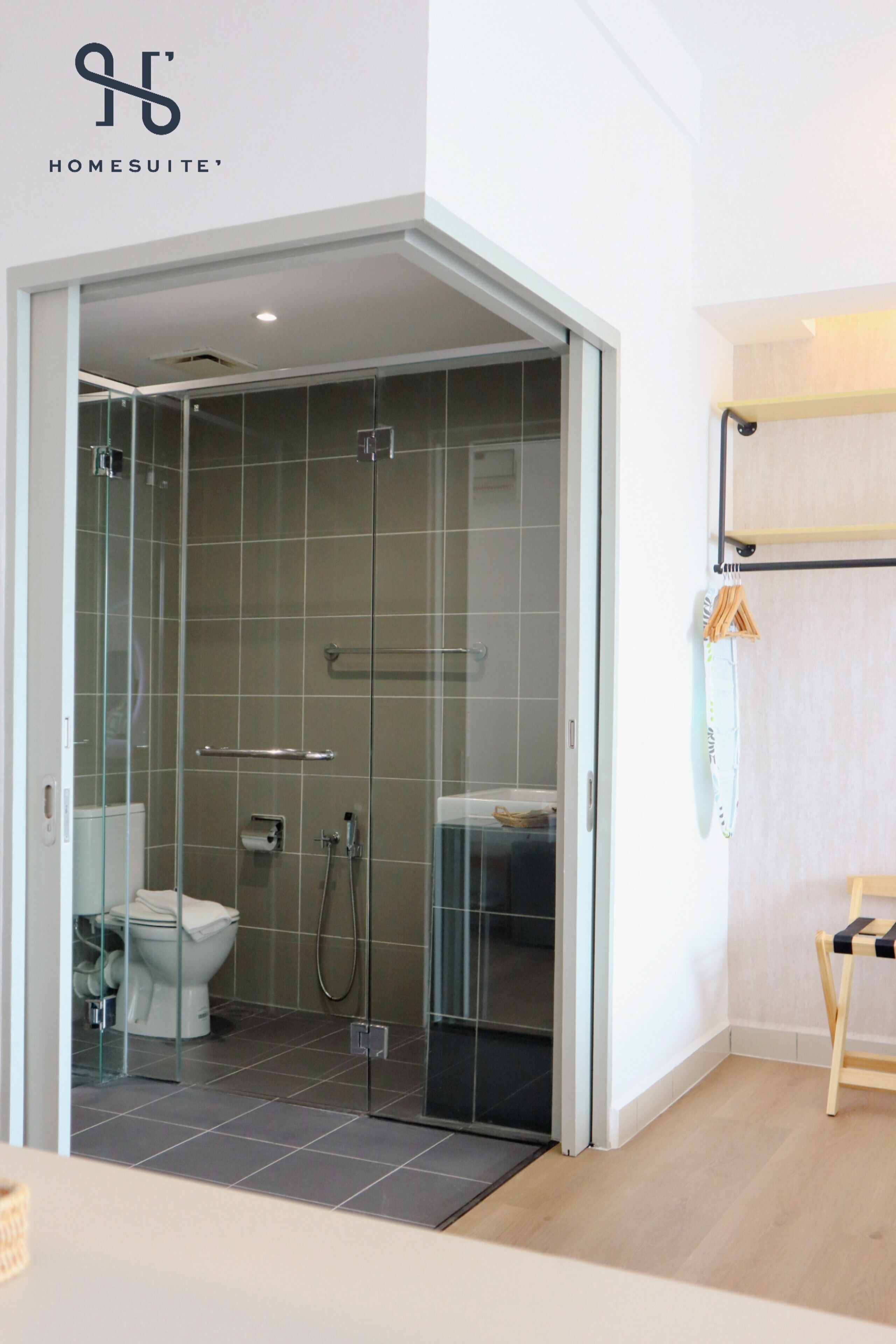 Un baño moderno con ducha acristalada, inodoro y banco de madera.