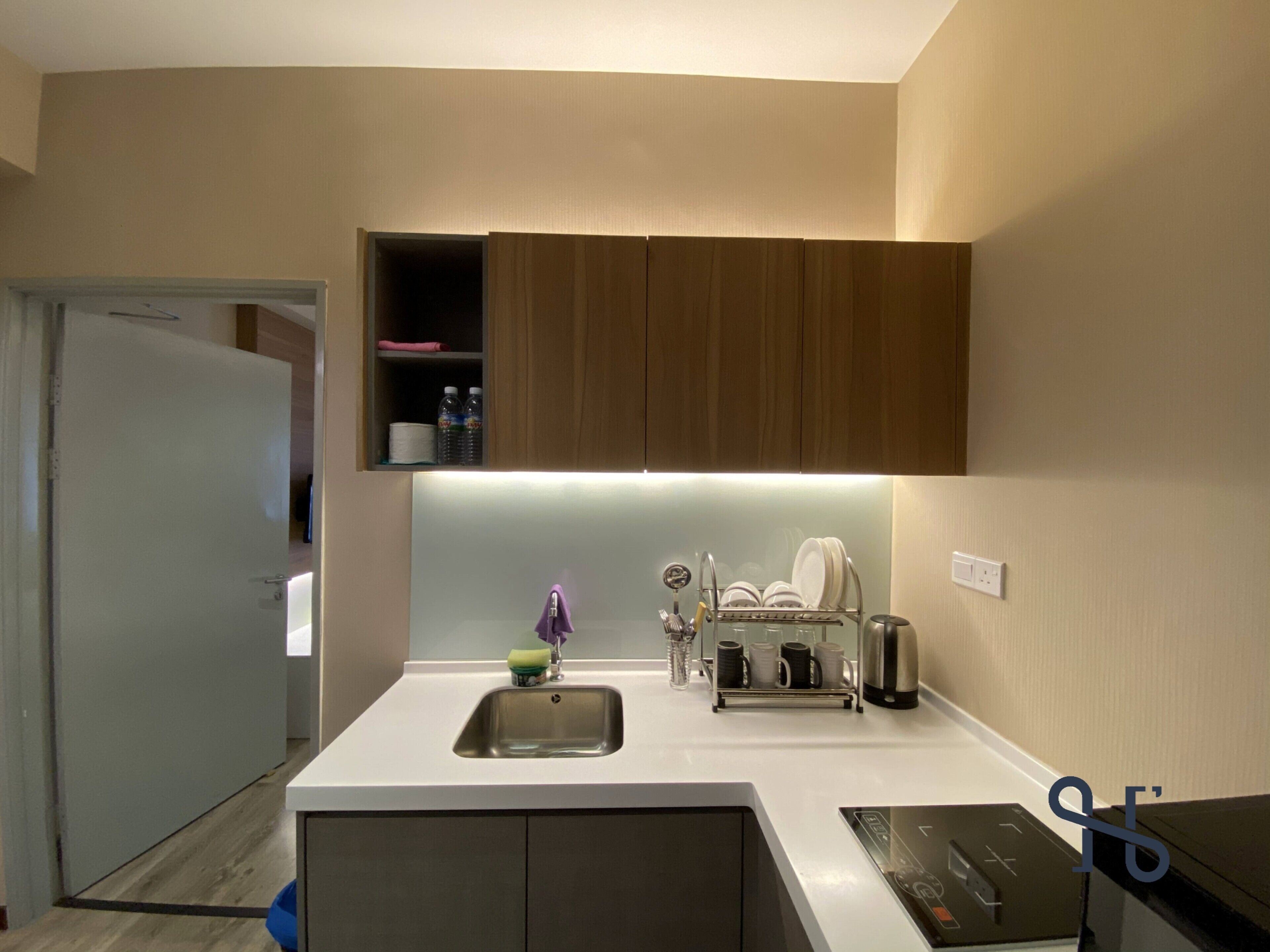 A modern kitchen with a white countertop, stainless steel sink, and wooden cabinets.