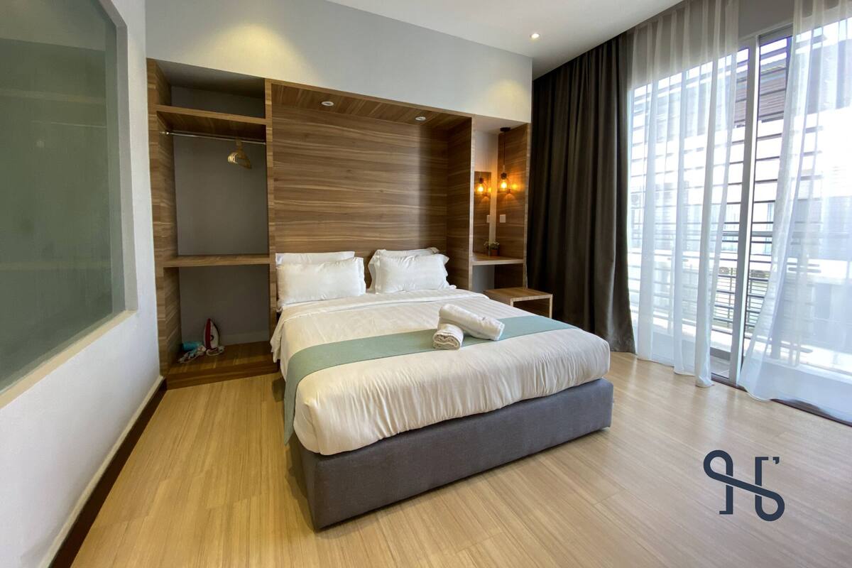 Une chambre d’hôtel moderne dotée d’un grand lit, d’étagères intégrées et d’une grande fenêtre avec des rideaux.