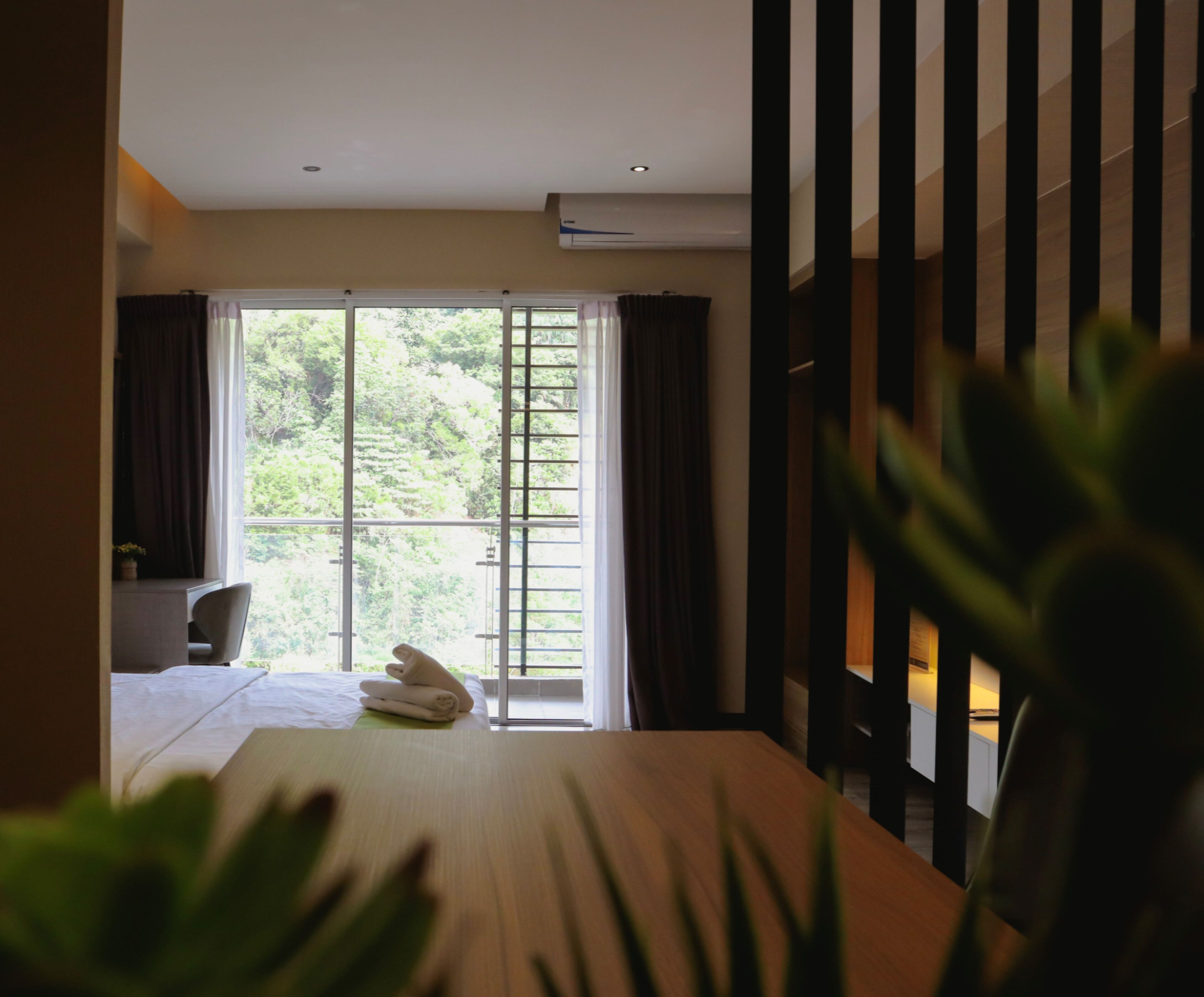 A hotel room with a bed, a desk, and a large window with curtains.