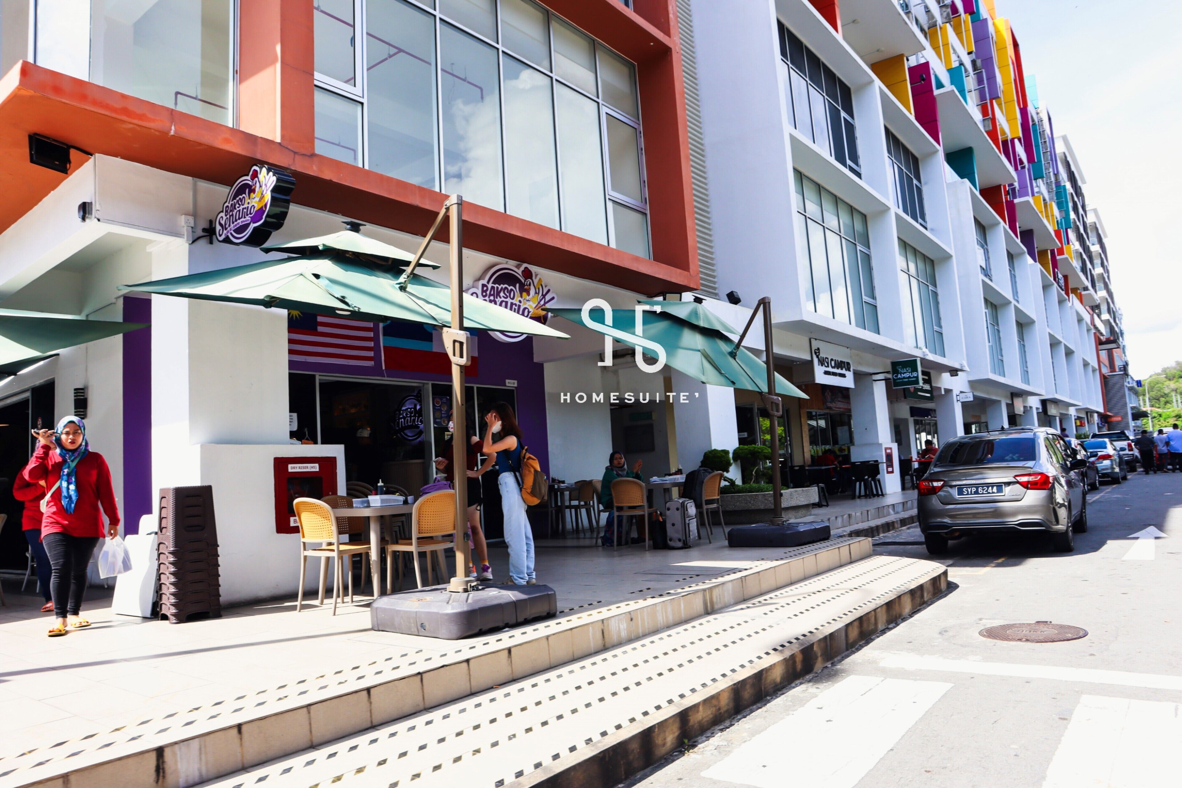 A hotel with outdoor seating and a storefront.