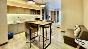 A modern kitchen with a dining area, a sofa, and a TV.
