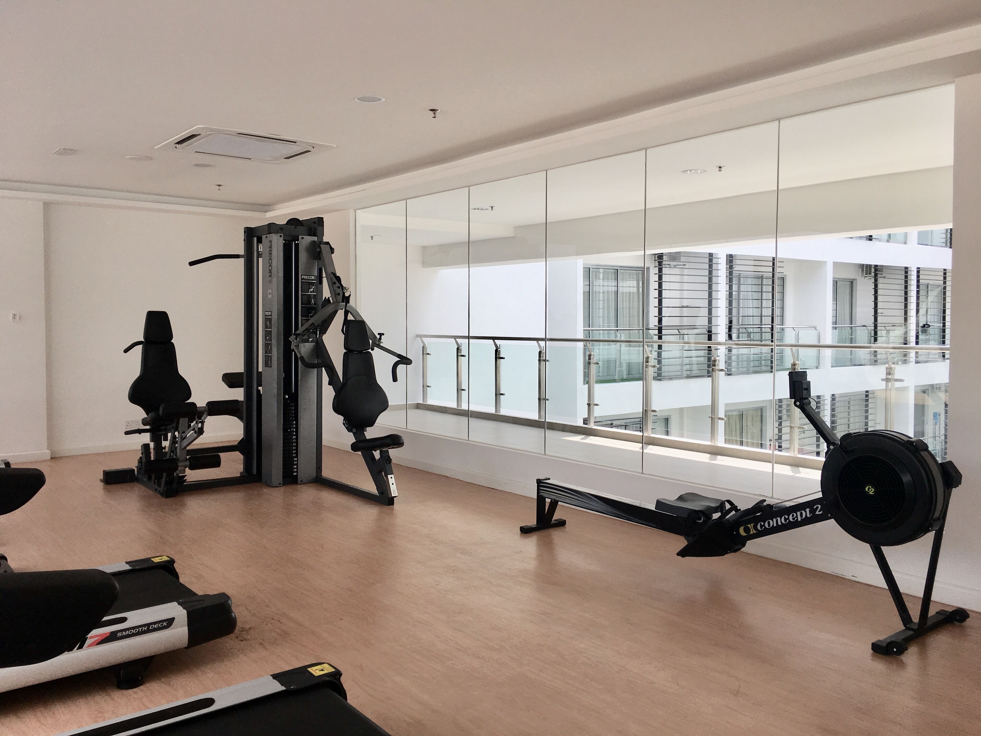 Une salle de sport moderne équipée de machines de cardio, de poids et d’un rameur.