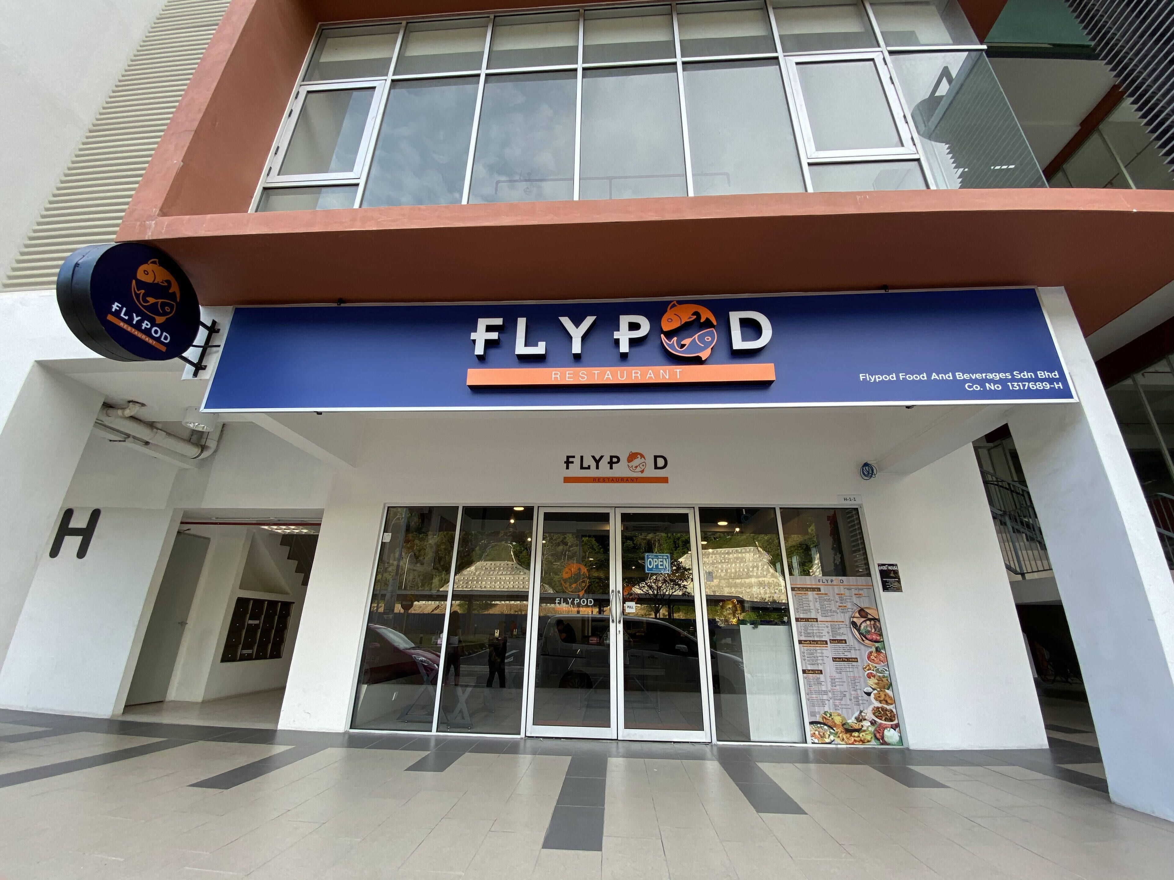 The exterior of Flypod Restaurant with a blue sign, large windows, and a visible entrance.