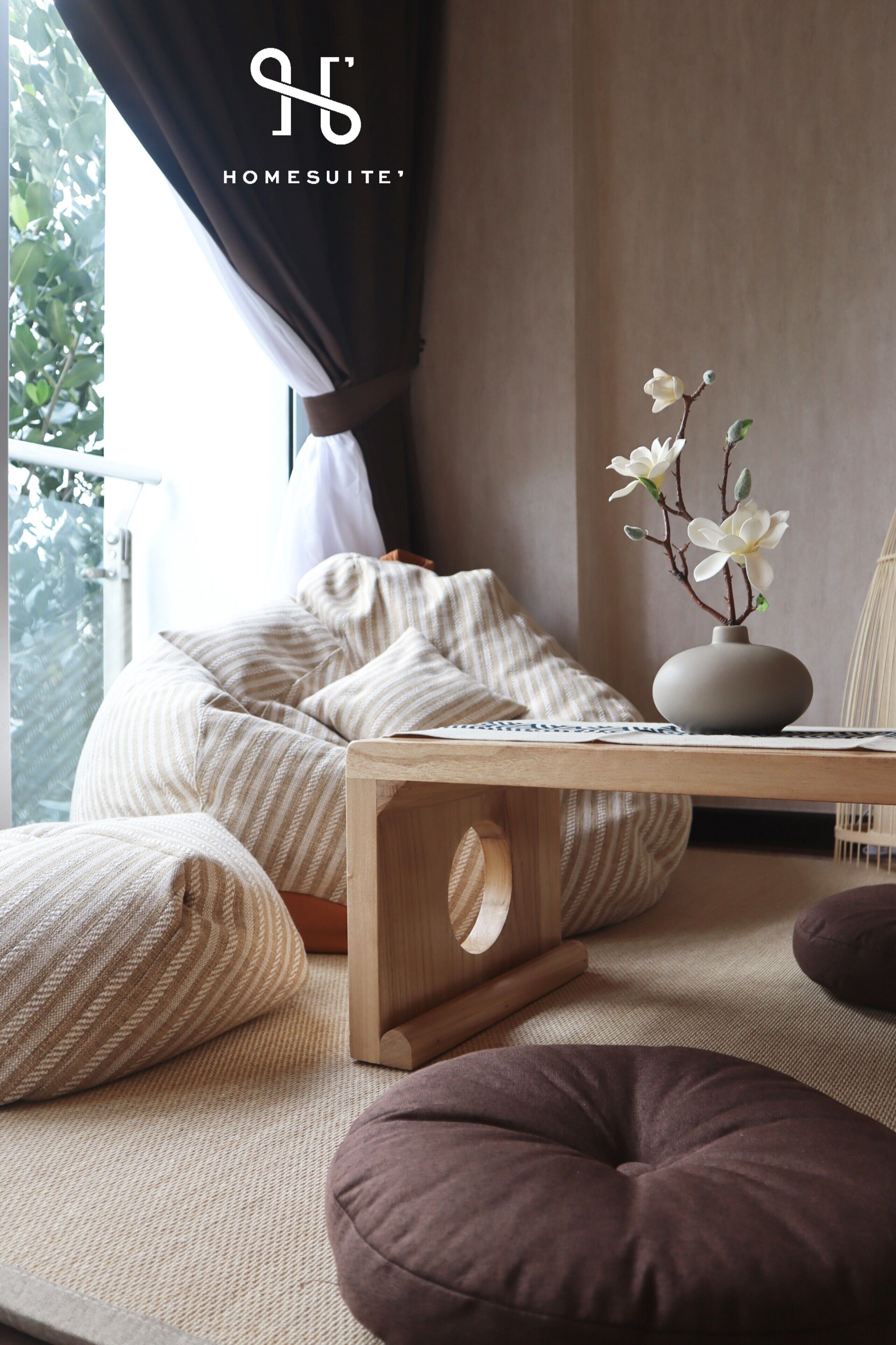 A cozy living area with a sofa, cushions, a small table, and a vase with flowers.