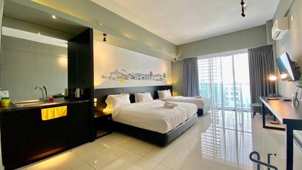A modern hotel room with a large bed, a desk, a flat-screen TV, and a cityscape artwork on the wall.