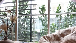 A cozy room with a large window, a wooden table, and a comfortable sofa.