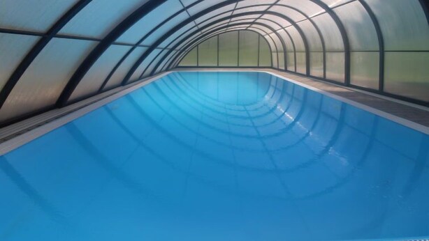 An indoor swimming pool with a curved ceiling and glass walls.