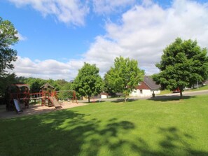 A playground with swings and a slide, surrounded by green grass and trees. - Holiday Hill 29 by Interhome (Cerny Dul/Cista)