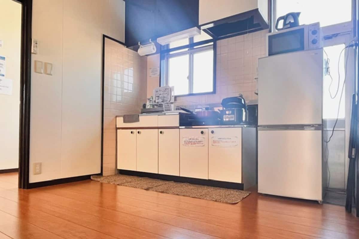 Una cocina funcional con suelo de madera, armarios blancos, microondas y refrigerador.