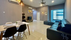Un salon moderne avec un coin repas, comprenant un canapé, des fauteuils, un téléviseur et des ventilateurs de plafond.