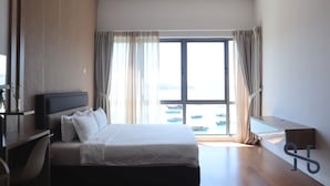 Une chambre d’hôtel moderne, dotée d’un grand lit, d’un bureau et offrant une vue sur les bateaux par la fenêtre.