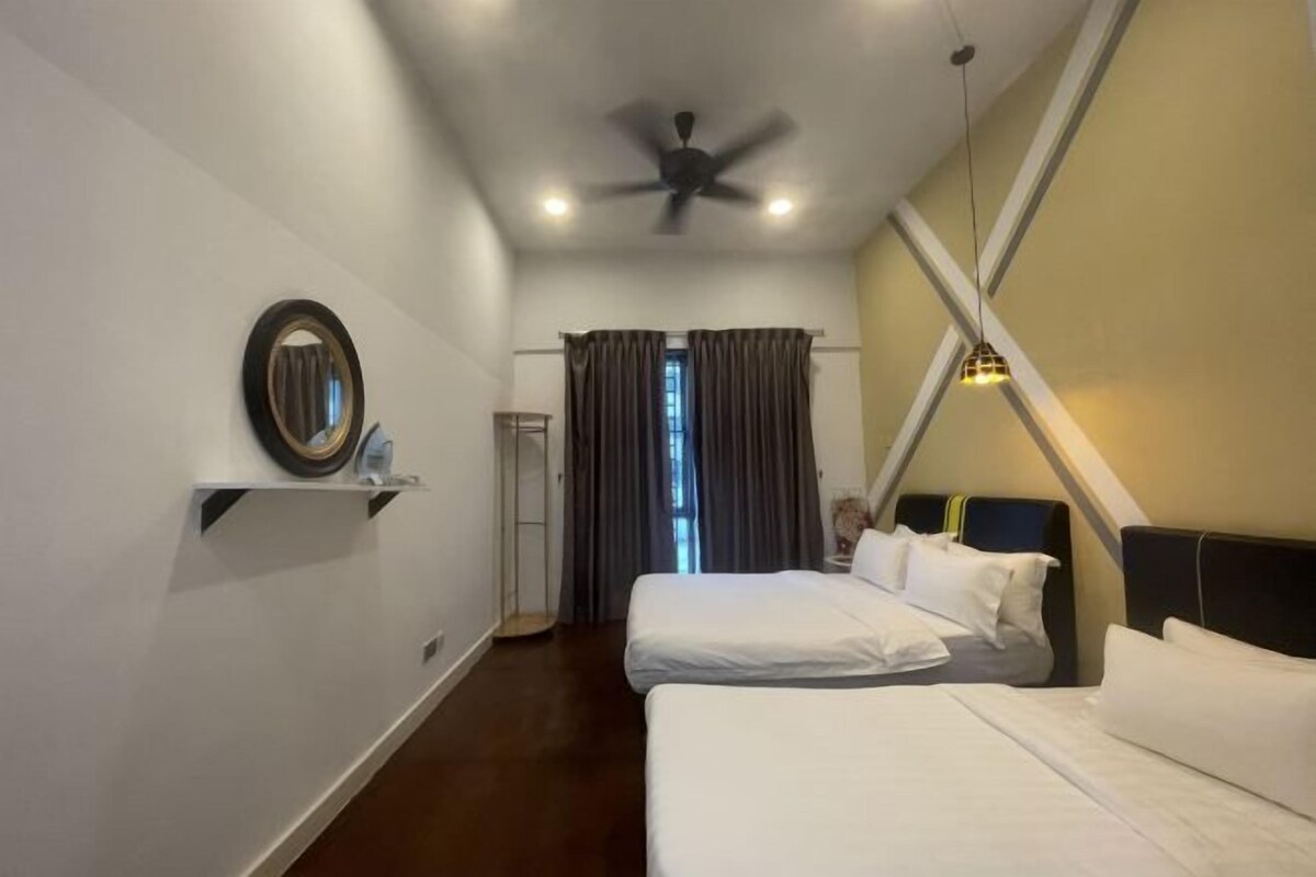 Quarto com duas camas, um ventilador de teto, um espelho e uma janela com cortinas.