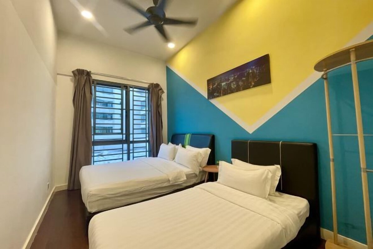 Habitación de hotel con dos camas, un ventilador de techo, una ventana con cortinas y un cuadro en la pared.
