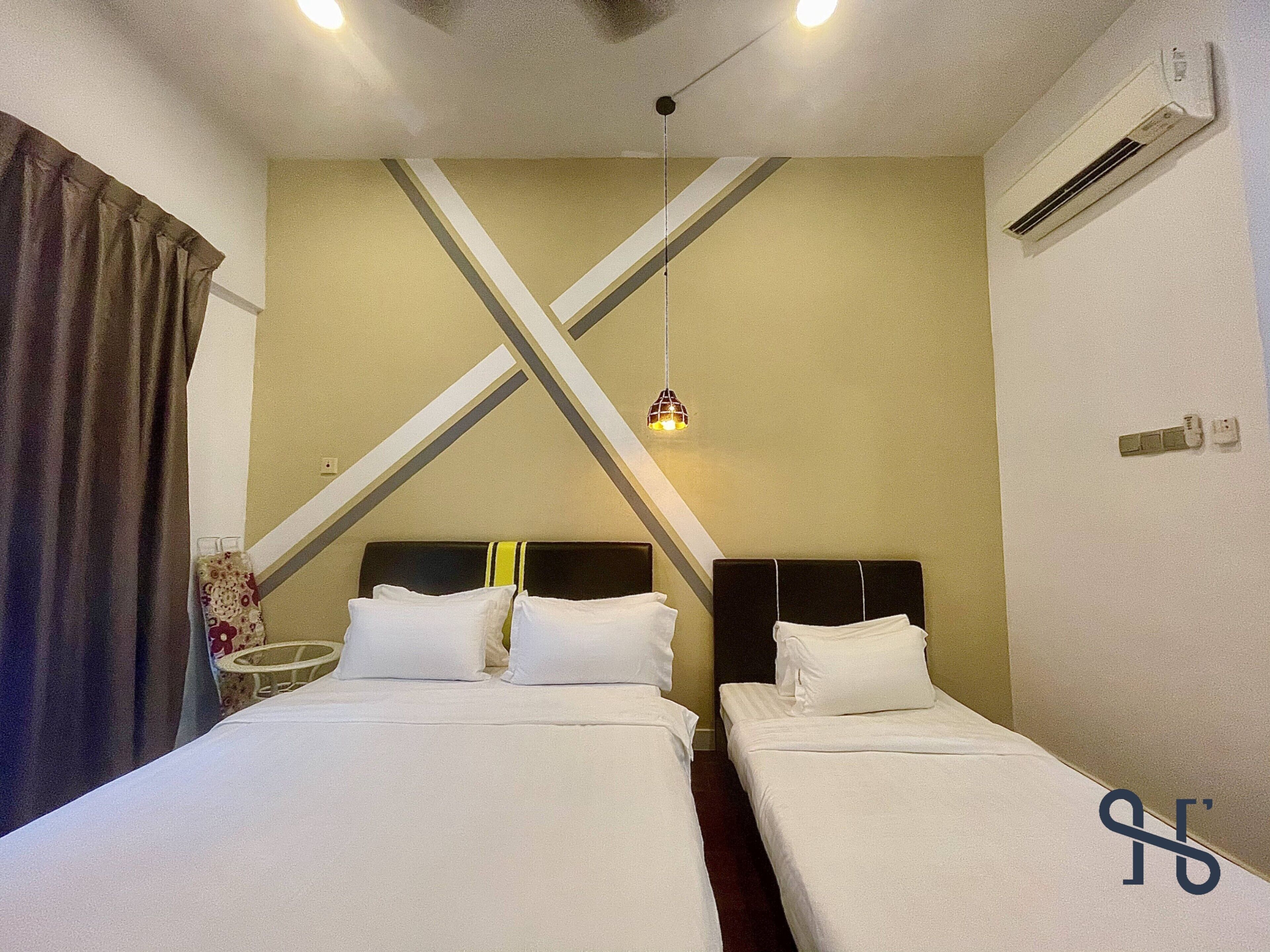 A hotel room with two beds, a hanging light fixture, an air conditioning unit, and a curtain.