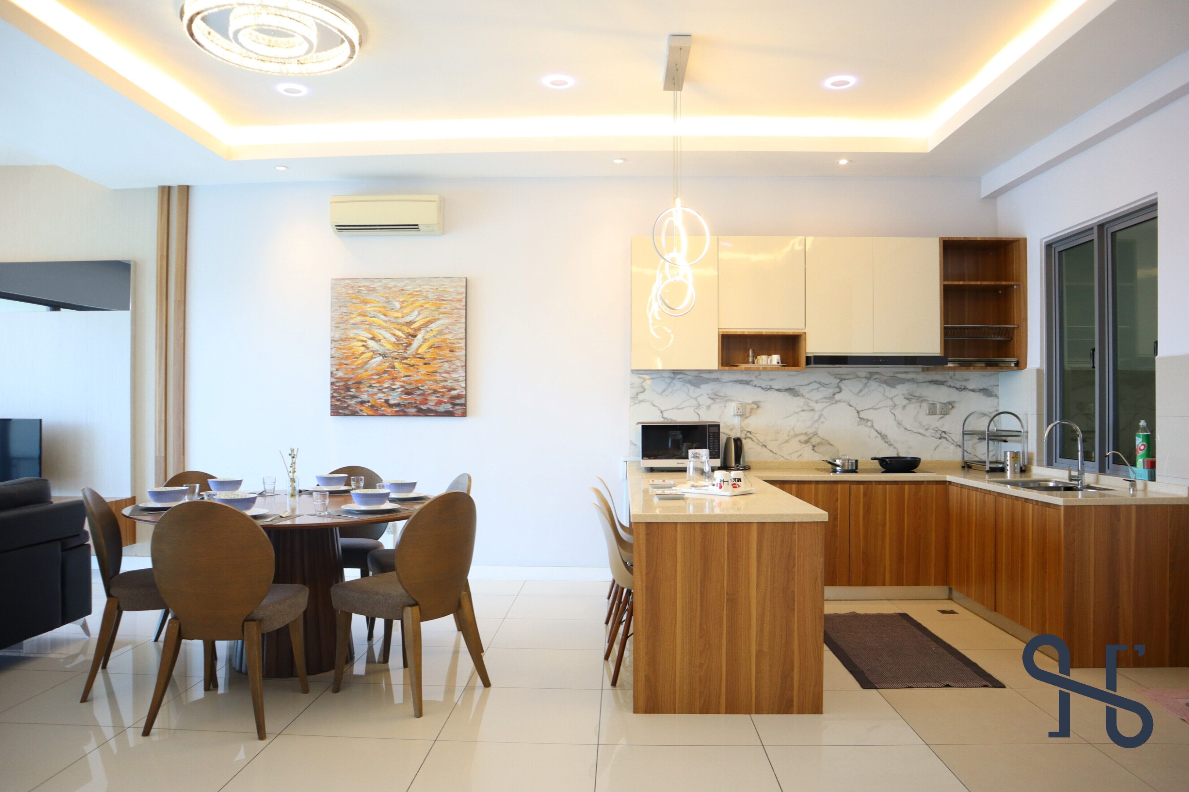 A modern kitchen with wooden cabinets, a marble countertop, and a dining area with a table and chairs.