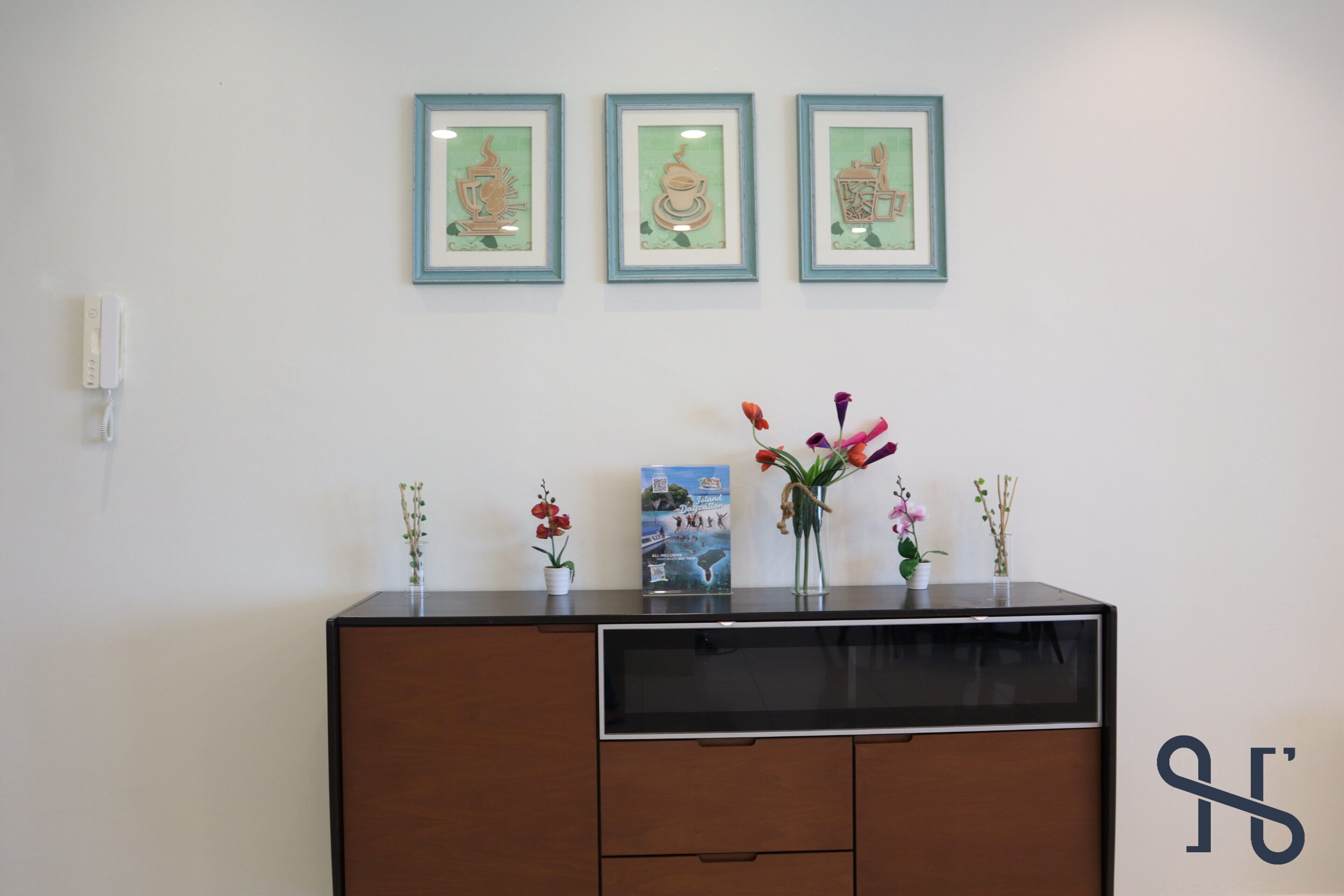 A reception desk with framed artwork, a vase with flowers, and a welcome brochure.