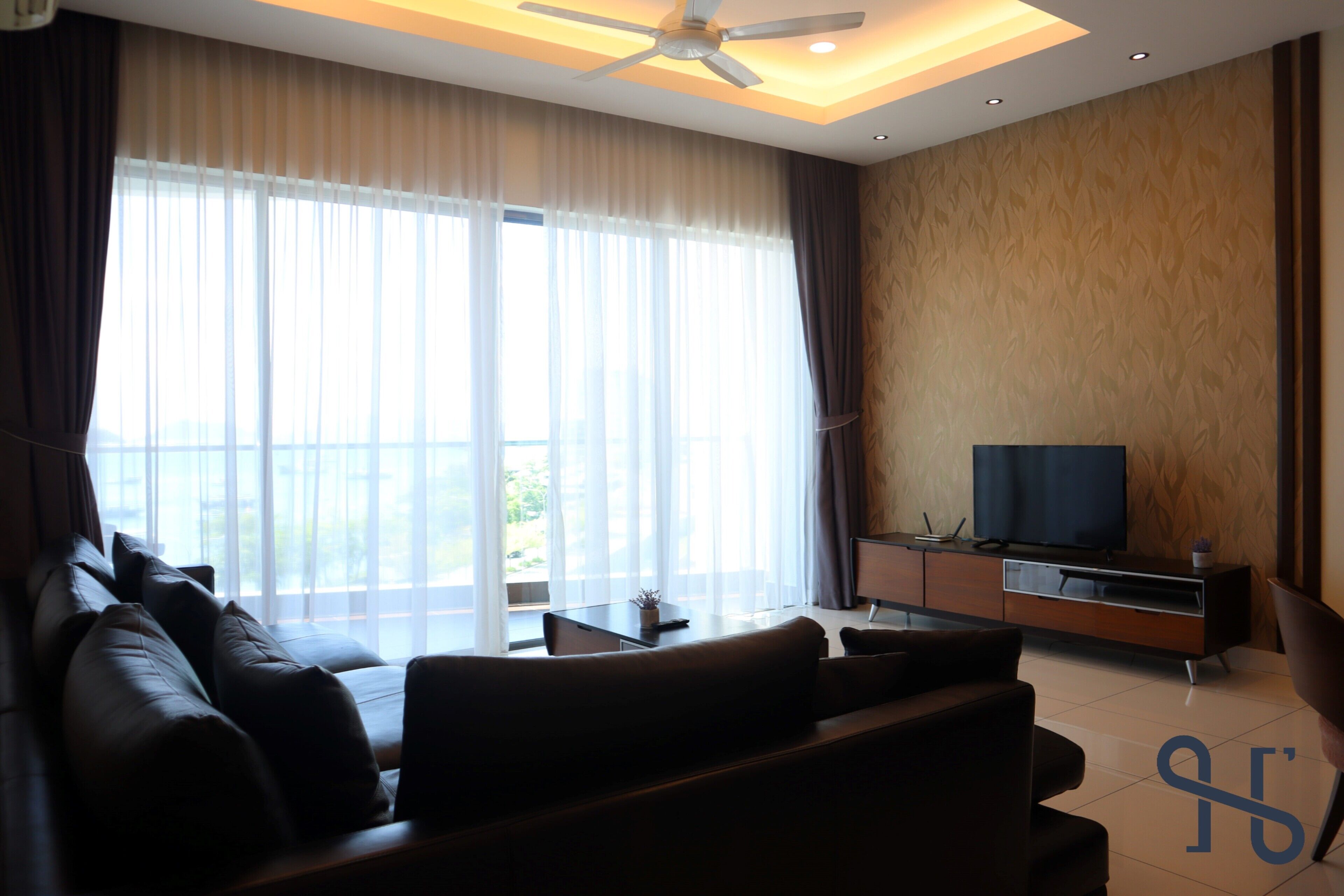 A modern living room with a sofa, TV, and a large window with curtains.