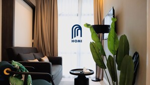 A modern living room with a sofa, a coffee table, a chair, and a large plant. - Homi Oasis 和逸绿洲 (Kota Kinabalu)