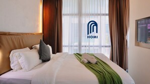 A hotel room with a neatly made bed, a green throw blanket, and a view of the city through large windows. - Homi Oasis 和逸绿洲 (Kota Kinabalu)