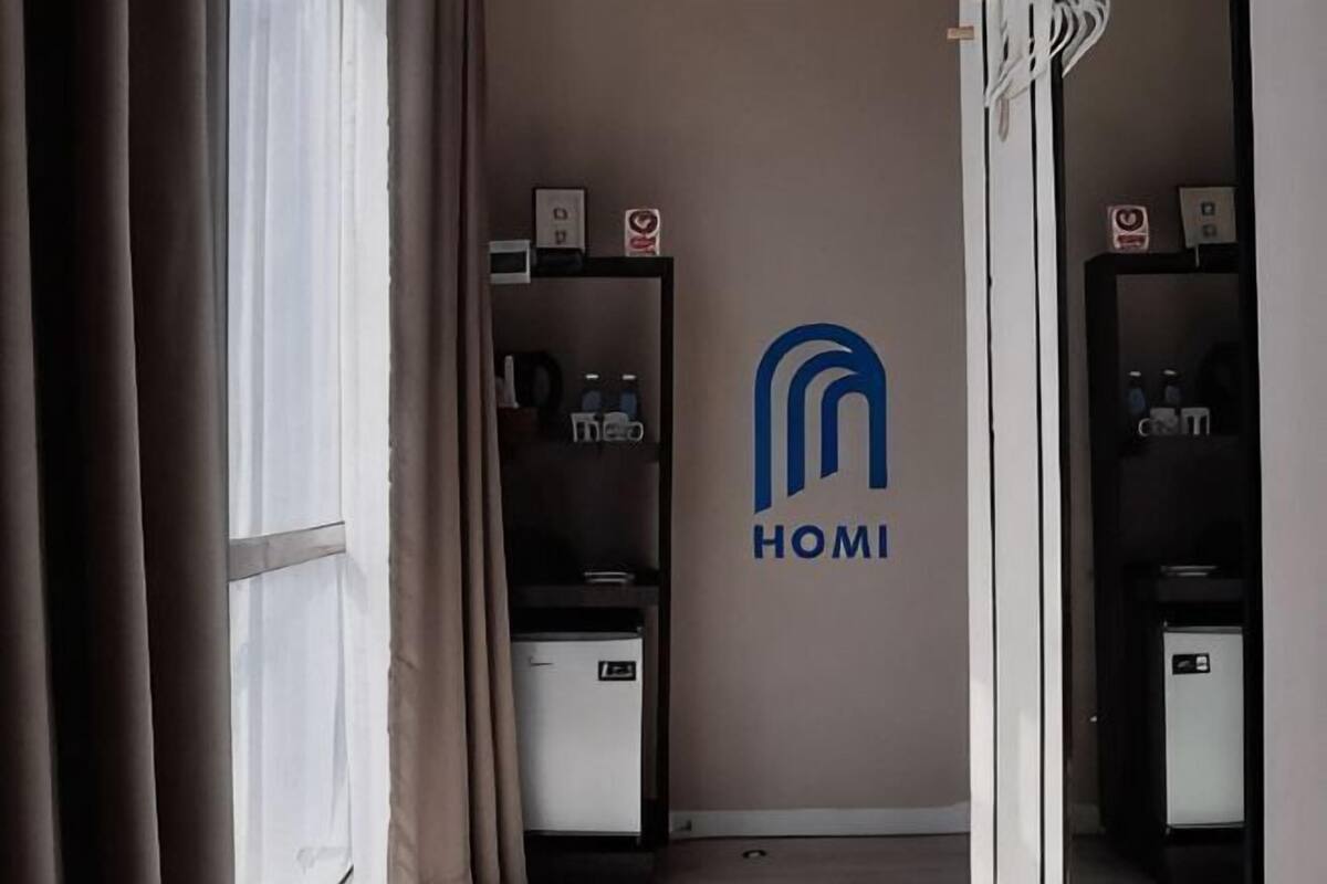 A hotel corridor with a logo on the wall, a reception desk, and a minibar.