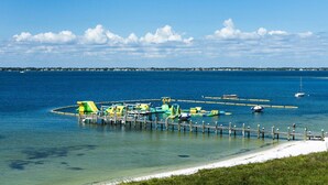 Eine Pier mit bunten Wasserfahrzeugen und einem Strand im Hintergrund.