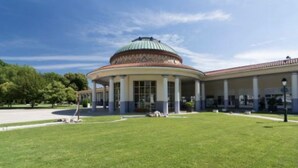Un bâtiment doté d’un dôme central, d’un porche et d’une pelouse bien entretenue.